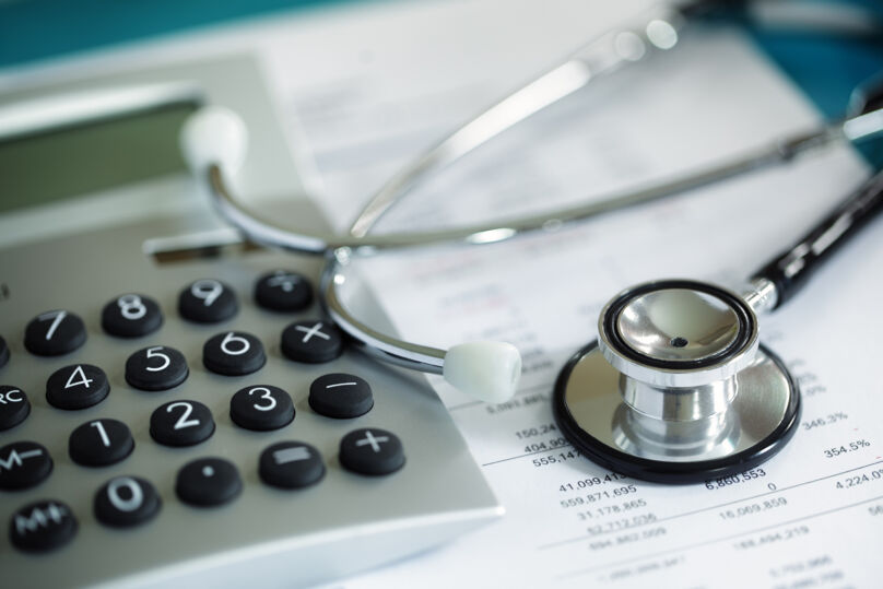 Na imagem: calculadora e estotoscópio sob documento médico