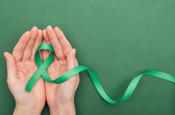 Imagem: pessoa segurando símbolo de conscientização do Abril Verde